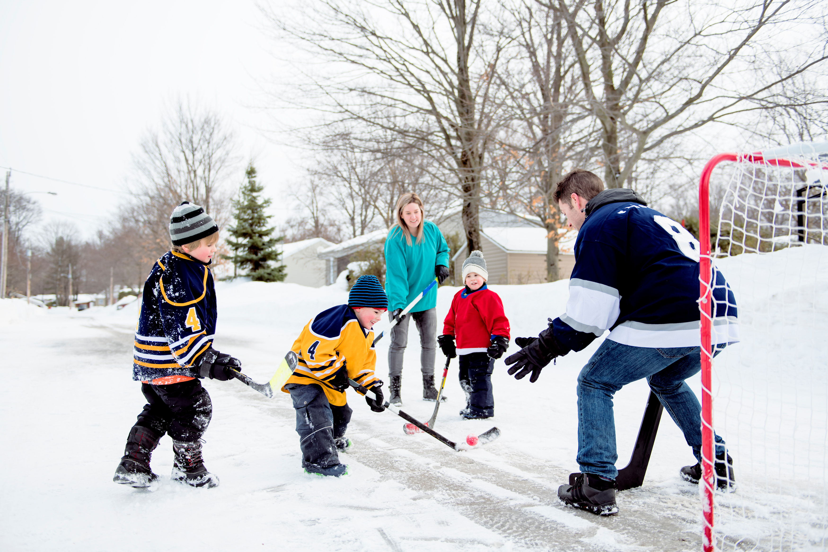 Family playing hockey outdoors in winter