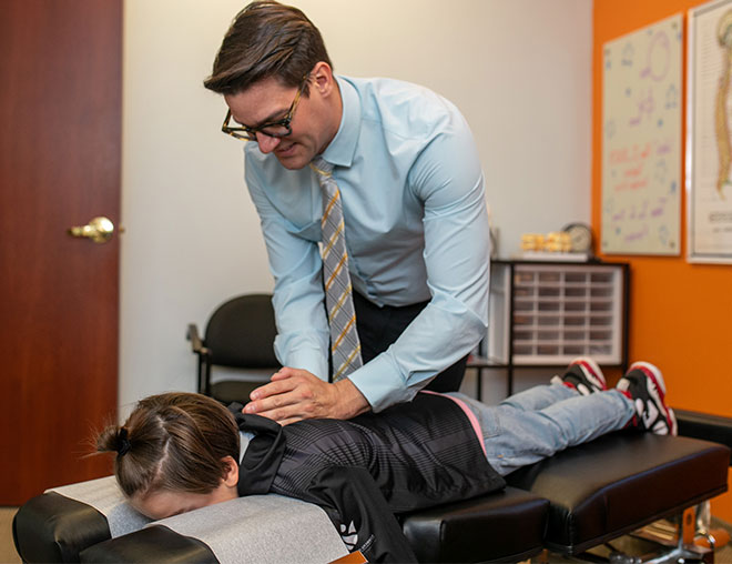 Dr. Bomber showing a patient a flexible chiropractic spine model